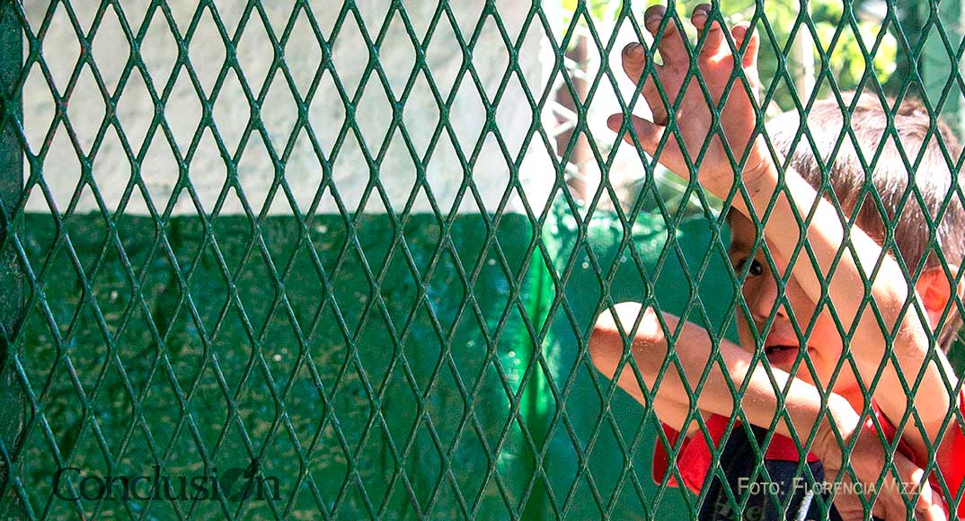 Barrios, rejas, infancias…el niño espía a la cámara que, a su vez lo espía a él.