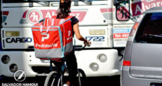 trabajadora de aplicación de pedidosya en bicicleta entre el tránsito